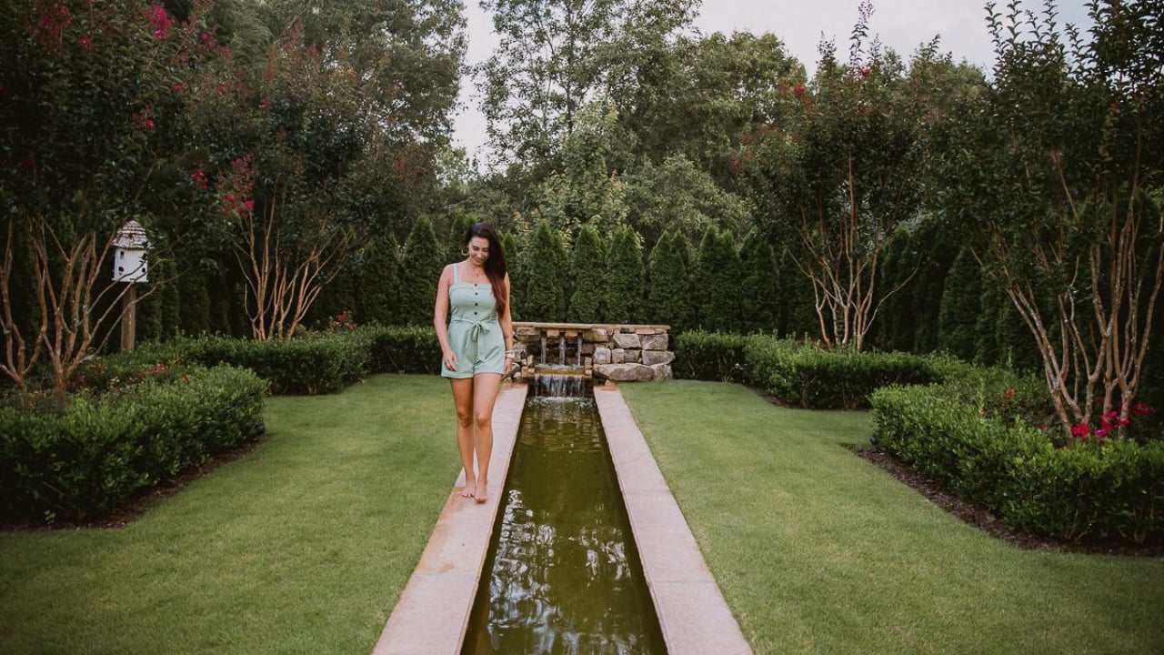 CeCe wearing a green jumpsuit, walking along a pool