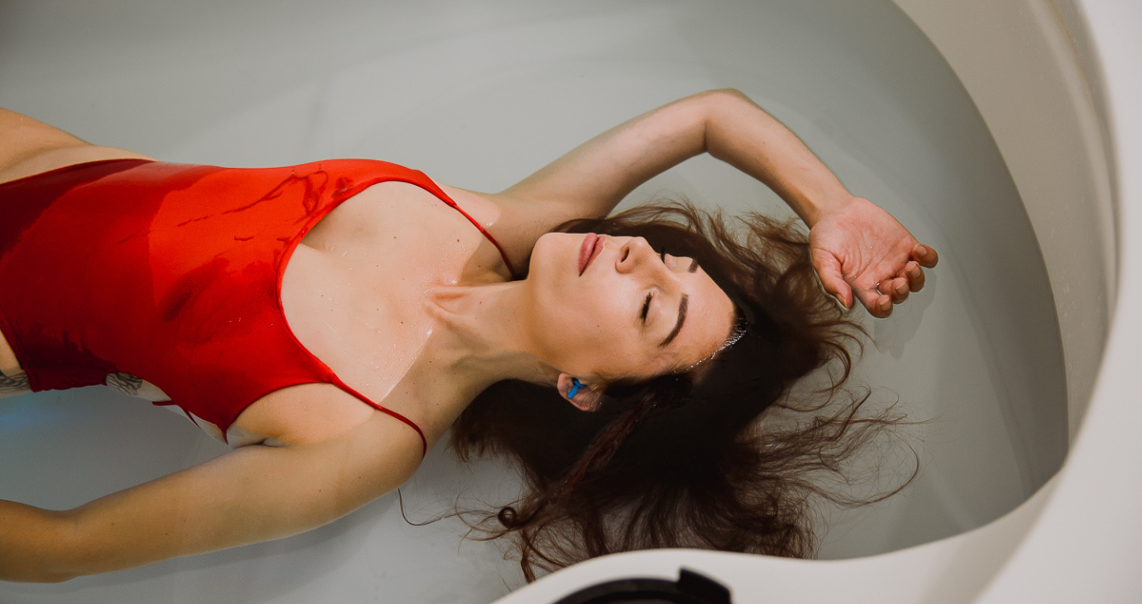 CeCe floating in a tank wearing a red swimsuit