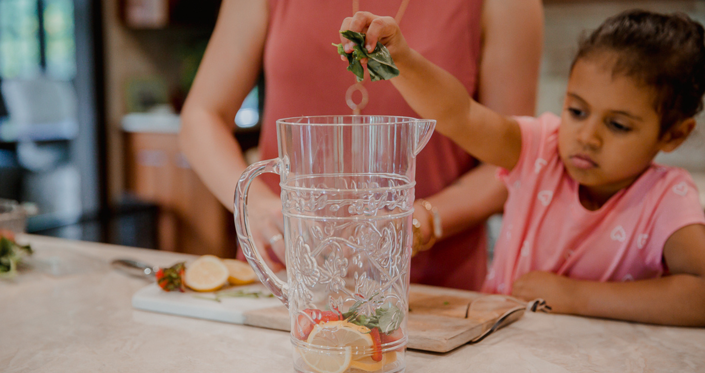 CeCe pouring water from a ceramic jug into two reusable cups