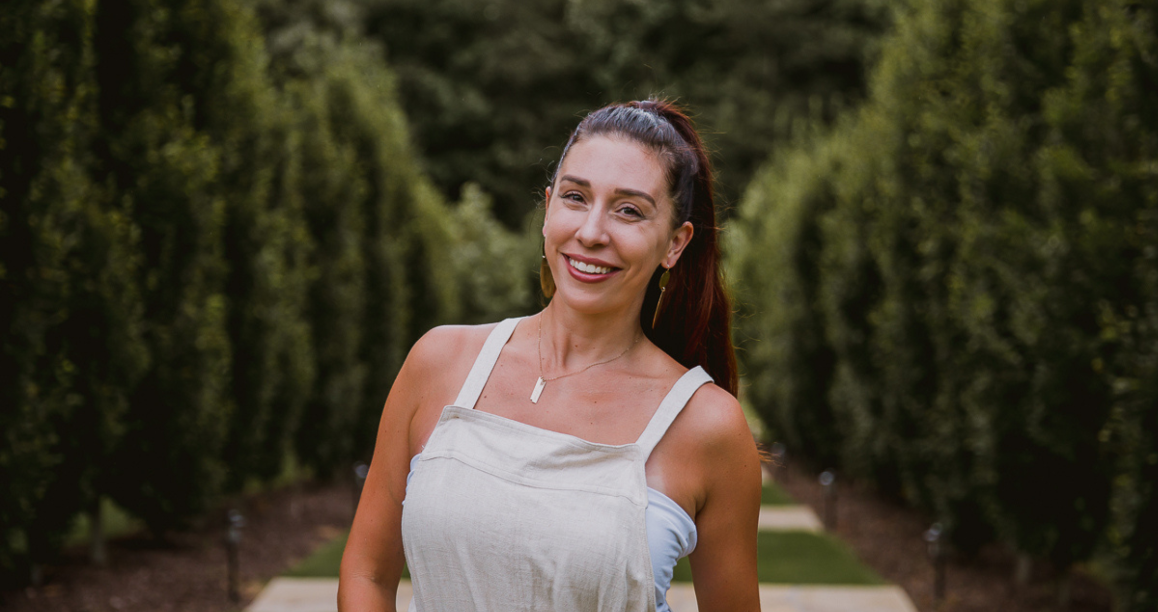 CeCe standing in a garden wearing white overalls